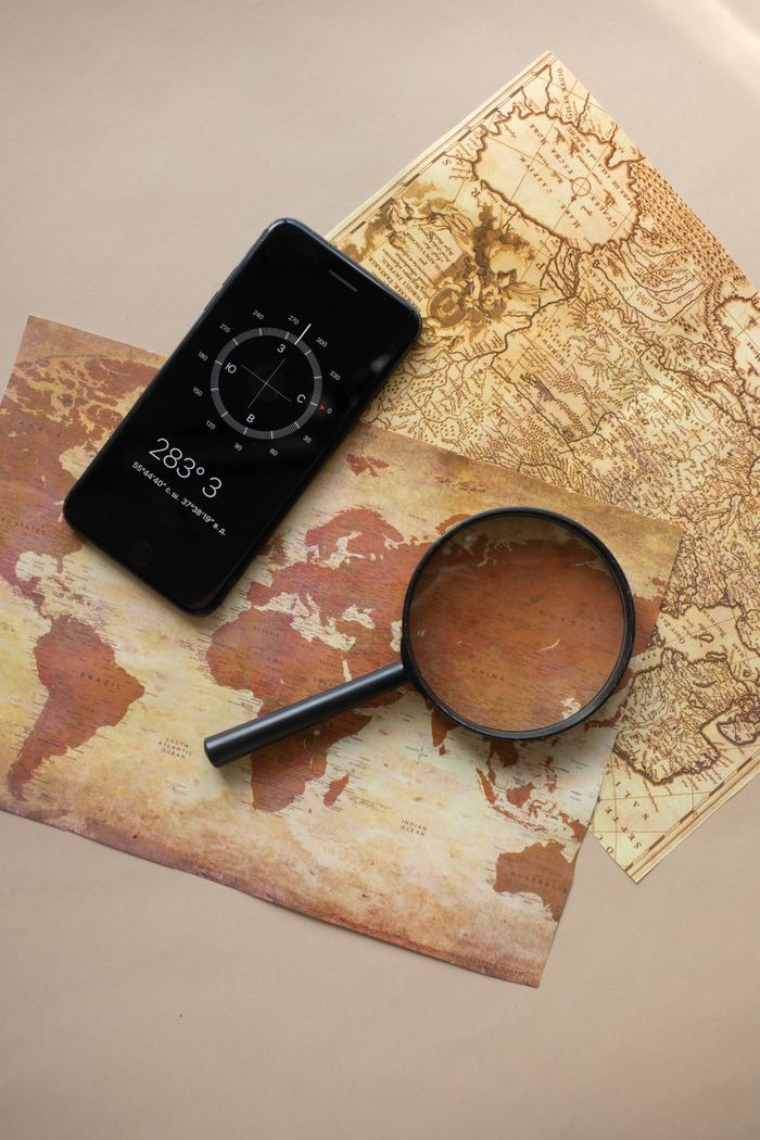 A smartphone with compass app and vintage map for adventure planning.